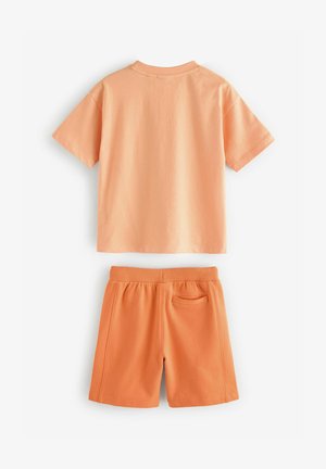 Koszulka z krótkim rękawem i okrągłym dekoltem oraz pasujące szorty w jasnopomarańczowym kolorze. Wykonana z miękkiej bawełny, o luźnym kroju. Szorty mają elastyczny pas.