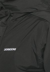 Chaqueta impermeable negra con una textura suave, con cierre de cremallera y logo bordado "DIDRIKSONS" en blanco.
