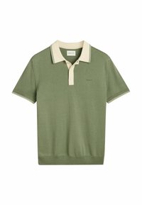 Polo vert avec un col beige et une finition latérale. Comprend une patte de boutonnage à deux boutons et un petit logo sur la poitrine. Matière en maille douce.