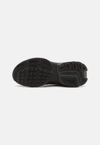 Suola di scarpe sportive nera in gomma testurizzata per una buona presa, con un disegno del battistrada definito e una costruzione resistente per la stabilità.