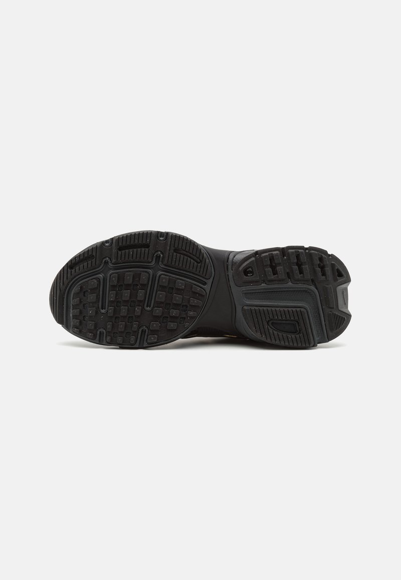 Semelle de chaussure de sport noire en caoutchouc texturé pour une adhérence, avec un motif de semelle défini et une construction durable pour la stabilité.