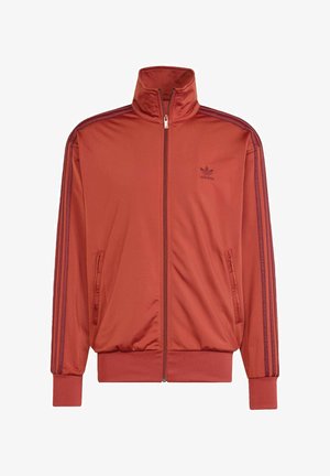 Piros poliészter zipzáras dzseki magas gallérral, két oldalsó zsebbel és ellentétes, sötétpiros csíkokkal a vállakon és az ujjakon.