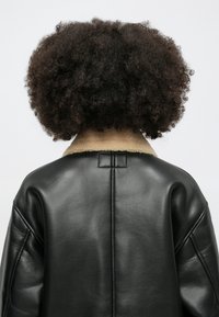 Czarna skórzana kurtka z kołnierzem z barana, z prostym krojem z tyłu i widocznymi szwami. Gładka powierzchnia i dopasowany krój.