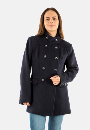Abrigo navy de doble botonadura con cuello levantado, botones plateados, bolsillos laterales y tela de lana texturizada. Presenta un corte ajustado y mangas largas.