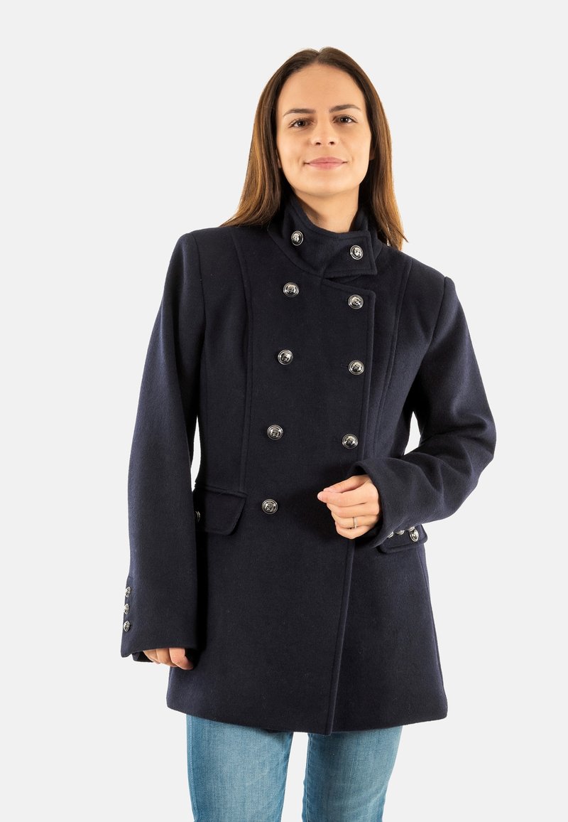 Cappotto doppiopetto blu navy con colletto alto, bottoni argentati, tasche laterali e tessuto in lana testurizzata. Presenta una vestibilità su misura e maniche lunghe.
