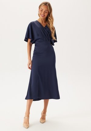 Abito di raso blu navy con scollatura a V, maniche corte con volant e vita adatta, che scivola in una gonna di lunghezza media con drappeggi sottili.