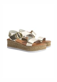 Sandales compensées métalliques en or avec des sangles croisées et une semelle en jute tissée. Elles possèdent une boucle décorative et une finition lisse et texturée.