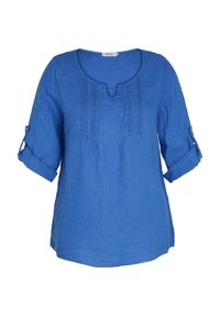 Blouse bleue à manches longues avec manches retroussées, col rond avec une petite encoche et coutures décoratives verticales à l'avant.