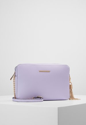 Prostokątna lawendowa torba na ramię z złotym łańcuszkowym paskiem, zamkiem błyskawicznym i małą złotą plakietką z logo z przodu.