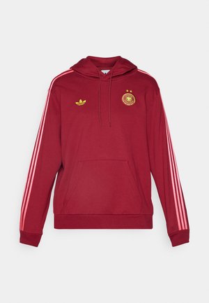 Felpa rossa con strisce laterali rosa, tasca a marsupio e coulisse regolabile. Presenta il logo Adidas e l'emblema della Germania in giallo.