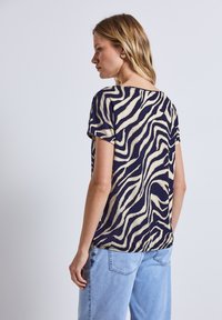 T-shirt a maniche corte di colore blu navy con stampa zebra in crema, dal taglio morbido e dalla trama sottile, mostrato da dietro.