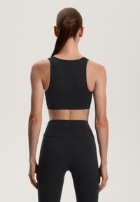 Sutien sport negru cu un design elegant, dotat cu bretele late și o textură netedă. Purtați-l împreună cu colanți înalți asortați.
