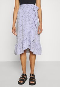 Vaaleanlaventelin värinen kietaisuhame, jossa on röyhelöhelma, pieni kukkakuosi ja sivusolmu. Yhdistetty mustiin remmisandaaleihin.