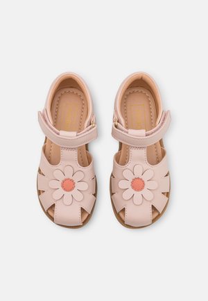 I sandali di pelle rosa chiaro presentano un design floreale sulla parte anteriore, dettagli intagliati e una tracolla regolabile con una fibbia dorata.