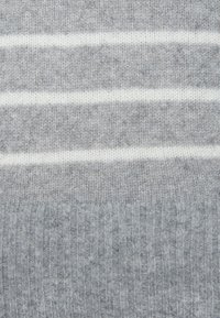 Grijze gebreide trui met horizontale witte strepen, met een geribbelde textuur aan de onderkant en een zachte, gladde stof.