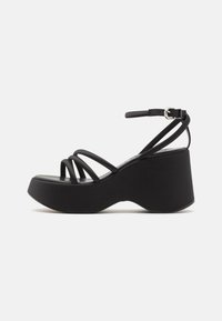 Black platform sandals with multiple thin straps and a buckled ankle strap. Features a wide, curved sole for support and stability.
