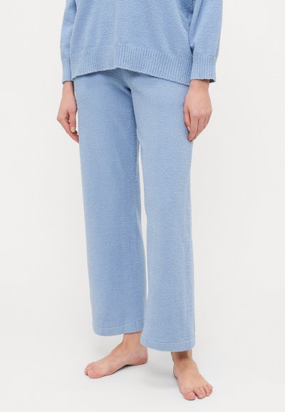Pantalons lounge en velours bleu clair avec une finition texturée, jambes larges et ourlets, associés à un pull assorti.