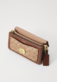 Portefeuille en cuir marron avec un devant en tissu à motifs, quincaillerie dorée, fermeture zippée et une étiquette détachable. Il possède une texture lisse et un design compact.