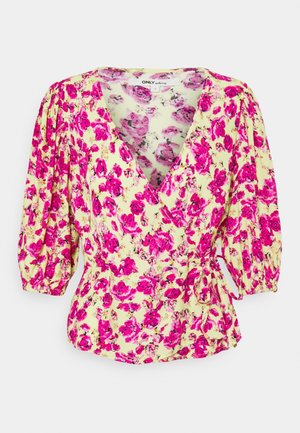 Bluse im Wickelstil mit pinkem Blumenmuster auf hellgelbem Hintergrund, mit gepufften Dreiviertelärmeln und seitlicher Bindung.