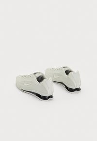 Balti skriešanas apavi ar teksturētu augšdaļu, ar melnu amortizētu zoli un elegantu dizainu. Iekļauts neliels Nike logo katrā pusē.
