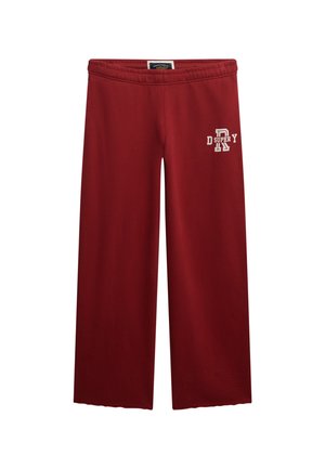 Red wide-leg sweatpants made of soft fabric, featuring an elastic waistband and white printed text on the left leg.