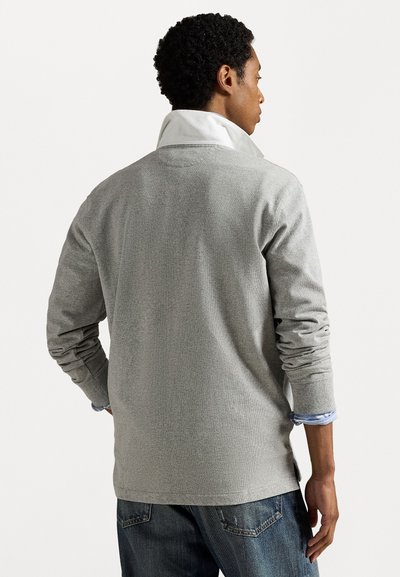 Grijze lange mouwen pullover met een textuurafwerking, voorzien van een witte kraag. Gecombineerd met een blauwe jeans voor een casual look.