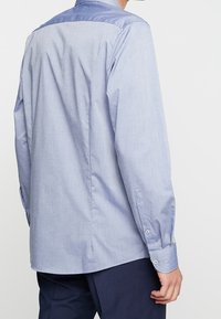 Lichtblauw, overhemd met lange mouwen en een gladde, contrasterende kraag. Gemaakt van een zachte stof met een subtiele textuur, met knoopmanchetten en een rechte zoom.