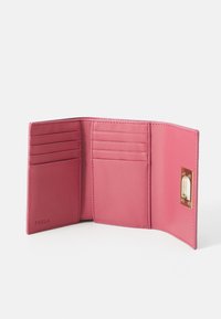 Pink leather wallet with multiple card slots and a golden hardware detail. Smooth texture and sleek design. Internal compartments visible.