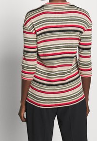 Hladký pletený svetr s horizontálními pruhy v růžové, červené, zelené a černé barvě. Má tříčtvrteční rukávy a kulatý výstřih. Texturovaná látka.