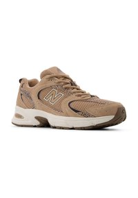 Scarpe sportive beige realizzate in materiali mesh e suede, caratterizzate da una spessa suola bianca, accenti neri e dettagli testurizzati sulla parte superiore.