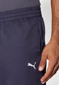 Tengerészkék sportnadrág, elasztikus derékkal, bal oldalon lévő zsebére hímzett fehér Puma logóval.