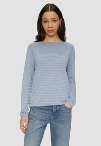 Helles blaues Langarmoberteil mit horizontaler Rippstruktur, runden Ausschnitt und lässiger Passform, kombiniert mit hellblauen Jeans.