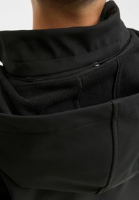 Giacca nera con colletto alto, caratterizzata da un morbido interno in pile, una superficie esterna liscia e dettagli di cucitura visibili.