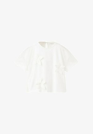 Blouse blanche à manches courtes avec encolure ronde et trois appliques florales 3D cousues sur le devant, avec une petite fermeture à bouton en forme d'œillet à l'arrière.