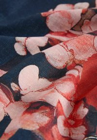 Stoff mit floralem Muster, der rosa und rote Blumen auf dunklem blauem Hintergrund zeigt, mit strukturierter Oberfläche und einem glatten, weichen Fall.