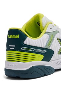 Biało-zielony but sportowy z siateczkową cholewką, wyściełanym kołnierzem, wsparciem pięty oraz teksturowaną szarą podeszwą z akcentującymi paskami.