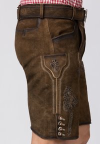 Bruna lädershorts med dekorativ broderi och en sidoficka, med silverknapp-accenter och en texturerad yta.