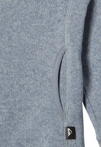 Suéter de punto gris con un acabado texturizado, que cuenta con un bolsillo lateral con un ribete gris y una pequeña etiqueta de logo cerca del dobladillo.
