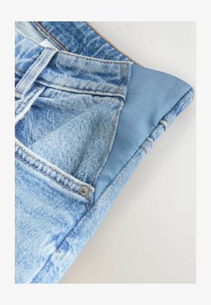 Spijkerbroek met lichtblauwe wassing, voorzien van een contrasterende elastische tailleband, metalen knopen en gedetailleerd stiksel langs de naden.