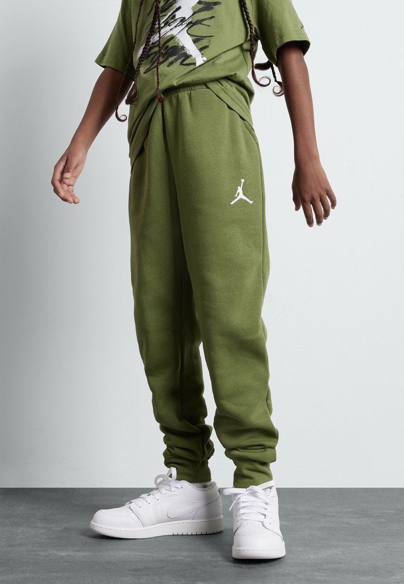 Gröna sweatpants med dragsko i midjan och sidofickor, prydda med en vit Jordan-logotyp. Matchas med vita träningsskor.