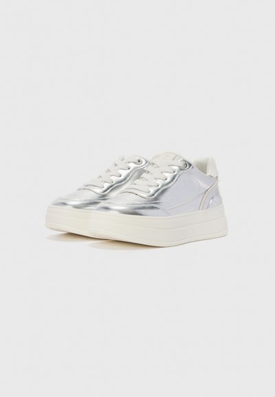 Silver sneakers med en glänsande ovandel, vita snören och en tjock vit gummisula. Har subtil branding och en mjuk textur.