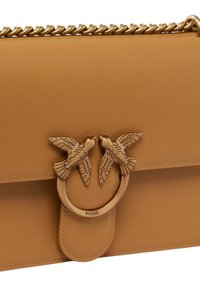 Borsa a tracolla in pelle color cammello con una catena e una chiusura decorativa in metallo che presenta due uccelli. Texture liscia con dettagli cuciti.