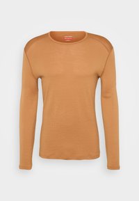 Chemise à manches longues dans une couleur caramel chaud, fabriquée en matériau doux, avec un col rond et des manches raglan. Texture lisse avec des coutures minimales.