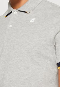 Polo grigio con finitura testurizzata, dotato di una pattina con due bottoni, logo ricamato e colletto con accenti blu navy e gialli.