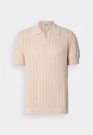 Polo en tricot beige à manches courtes, arborant un motif ajouré texturé et un col classique. Tissu doux et poignets côtelés.