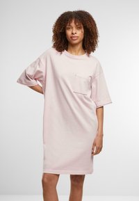 Rochie supradimensionată cu mânecă scurtă, din bumbac roz deschis, cu un buzunar pe piept și o textură fină, având un guler rotund și o croială lejeră.