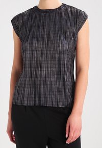 Metallic dark gray top with a textured vertical ribbed pattern, cap sleeves, and a round neckline, paired with black pants.
