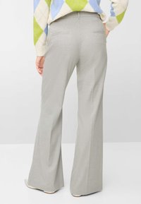 Grå bukser med vide ben i et struktureret stof, udstyret med baglommer og en glat talje. Stylet med en flerfarvet, mønstret sweater.