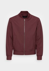 Chaqueta bomber burdeos con cuello, puños y dobladillo acanalados, cierre frontal de cremallera y dos bolsillos laterales.