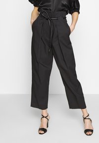 Pantaloni neri a vita alta con una vestibilità rilassata, dotati di un laccio regolabile in vita, tasche laterali e una texture liscia opaca.